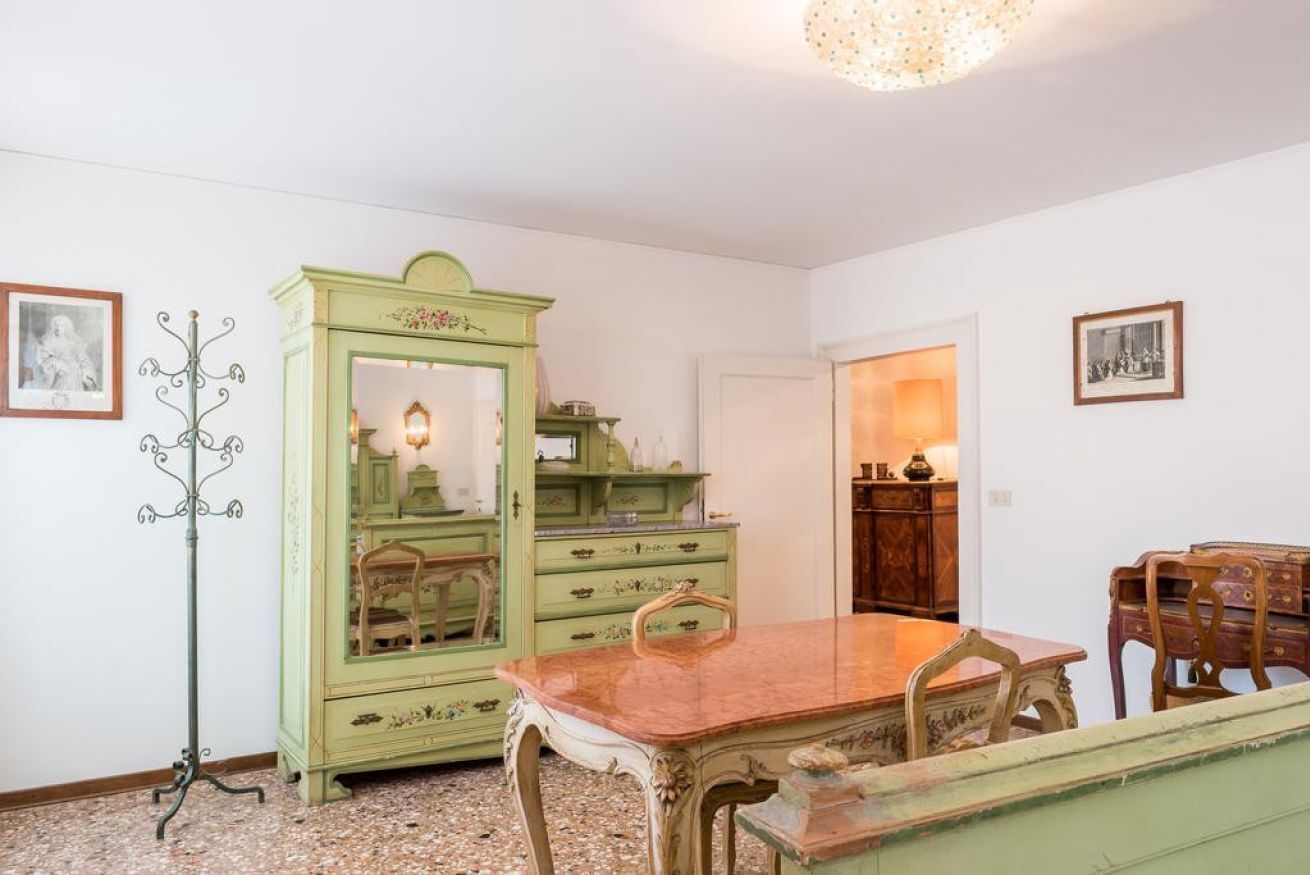 Ein Zimmer mit Esstisch, Stühlen, einem grünen Schrank und einem Garderobenhaken.