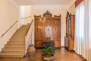 Una escalera con barandilla de madera, un amplio armario de madera y una planta en maceta al frente.