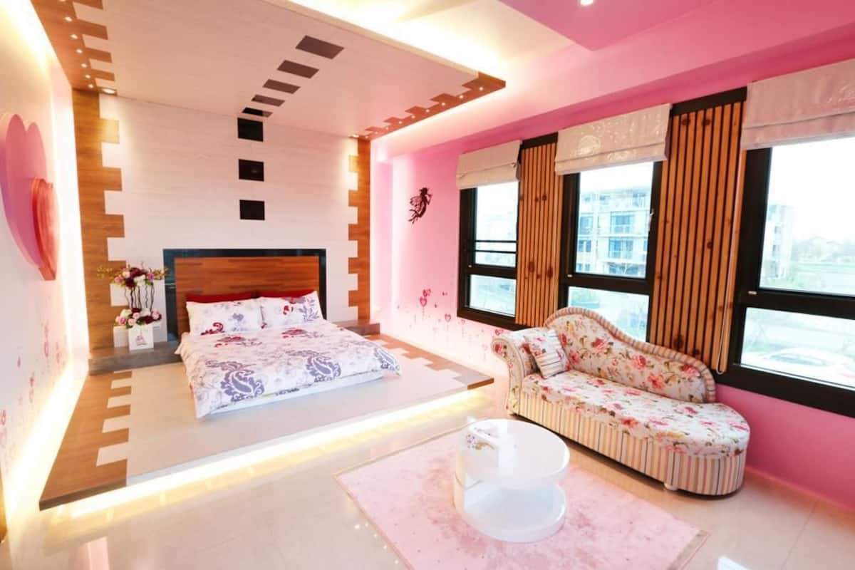 A modern bedroom with a bed, a sofa, and a large window.