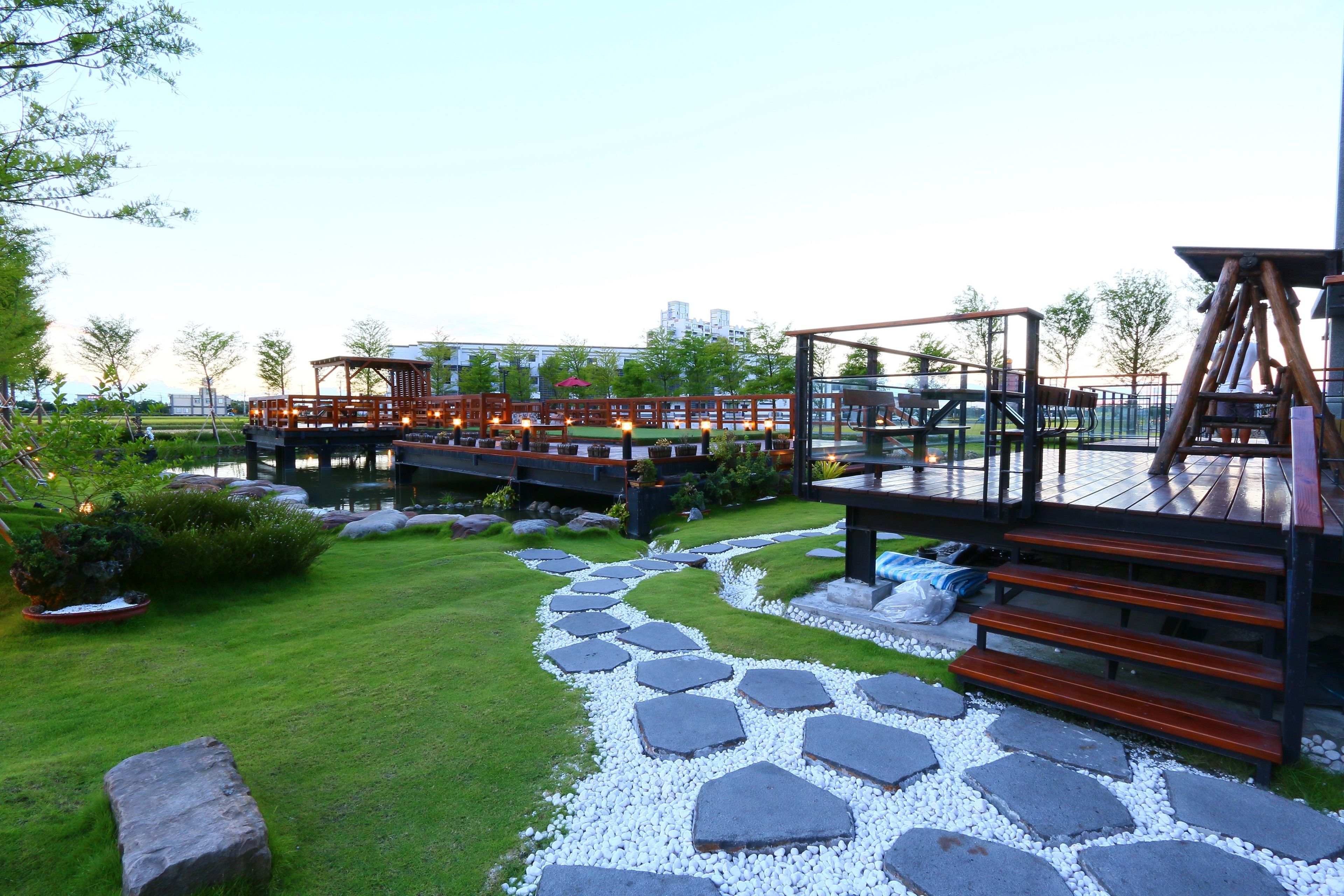 A landscaped garden with a stone pathway, wooden deck, and outdoor seating area.