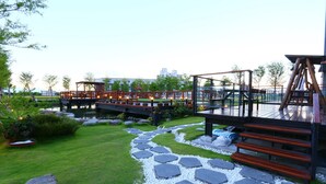 A landscaped garden with a stone pathway, wooden deck, and outdoor seating area. - Luoyuxuan (Wujie)
