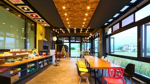 A restaurant with a long wooden table, colorful chairs, and a view through large windows. - Luoyuxuan (Wujie)