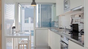 Une cuisine moderne dotée d’un îlot central, d’un four encastré et d’un luminaire suspendu.