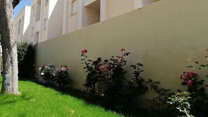 Un edificio con facciata piatta, diversi balconi e un giardino con rose rosa.
