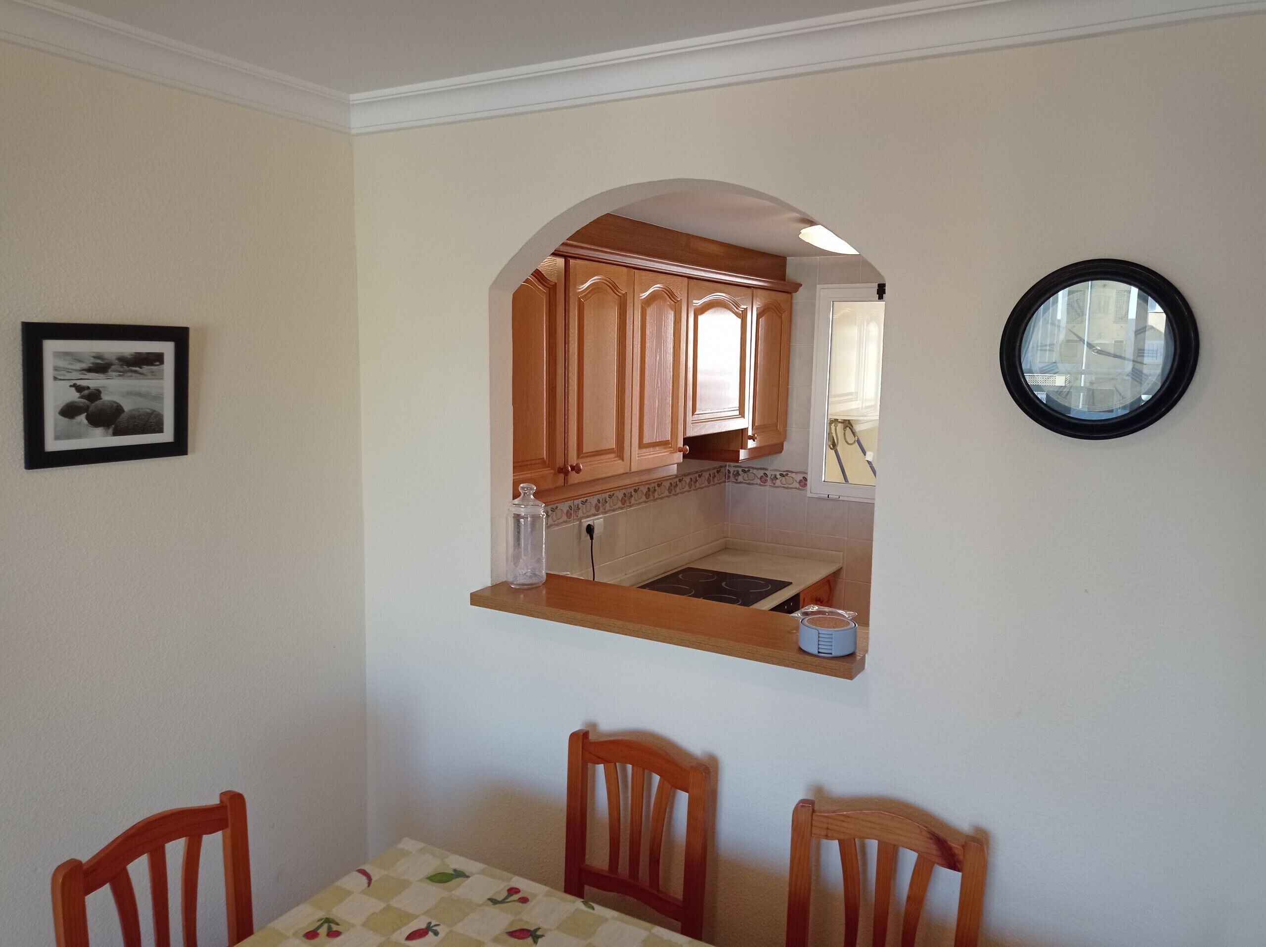 A dining area with a table, chairs, and a kitchen visible through an archway.