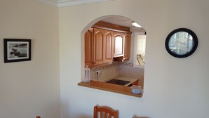 Zona pranzo con tavolo, sedie e cucina visibile attraverso un arco.