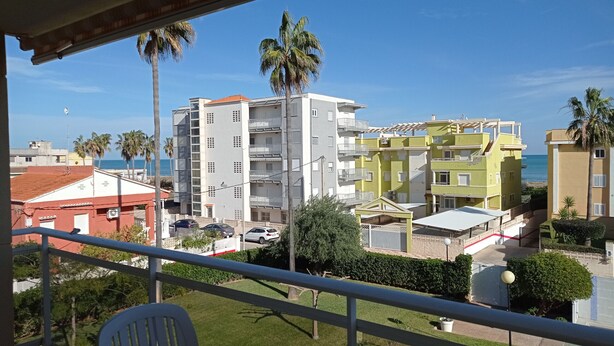Un balcone con vista su una zona residenziale, tra cui edifici a più piani e palme.