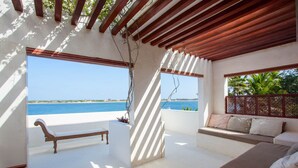 A balcony with a view of the sea, a wooden bench, and a sofa with cushions. - Luxury beachfront holiday house, pool garden all sea views, Forodhani House Lamu (Lamu)