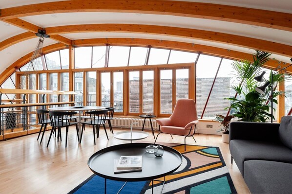 Una habitación amplia con techo alto, ventanas grandes, un comedor y una zona de estar acogedora.