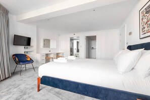 Una habitación de hotel moderna con una cama grande, televisión, escritorio y una silla.