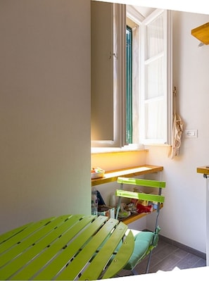 Ein kleiner, heller Raum mit Fenster, Schreibtisch und Stuhl.