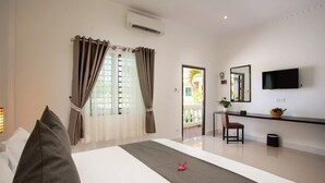 Una habitación de hotel moderna con una cama, un escritorio, una silla, un televisor y un ventanal con cortinas.