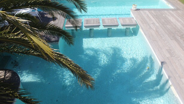 Vista despejada de una piscina con muelle de madera y palmeras.
