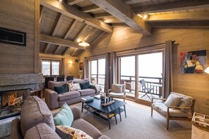 Una sala de estar acogedora con chimenea, asientos cómodos y ventanas amplias.