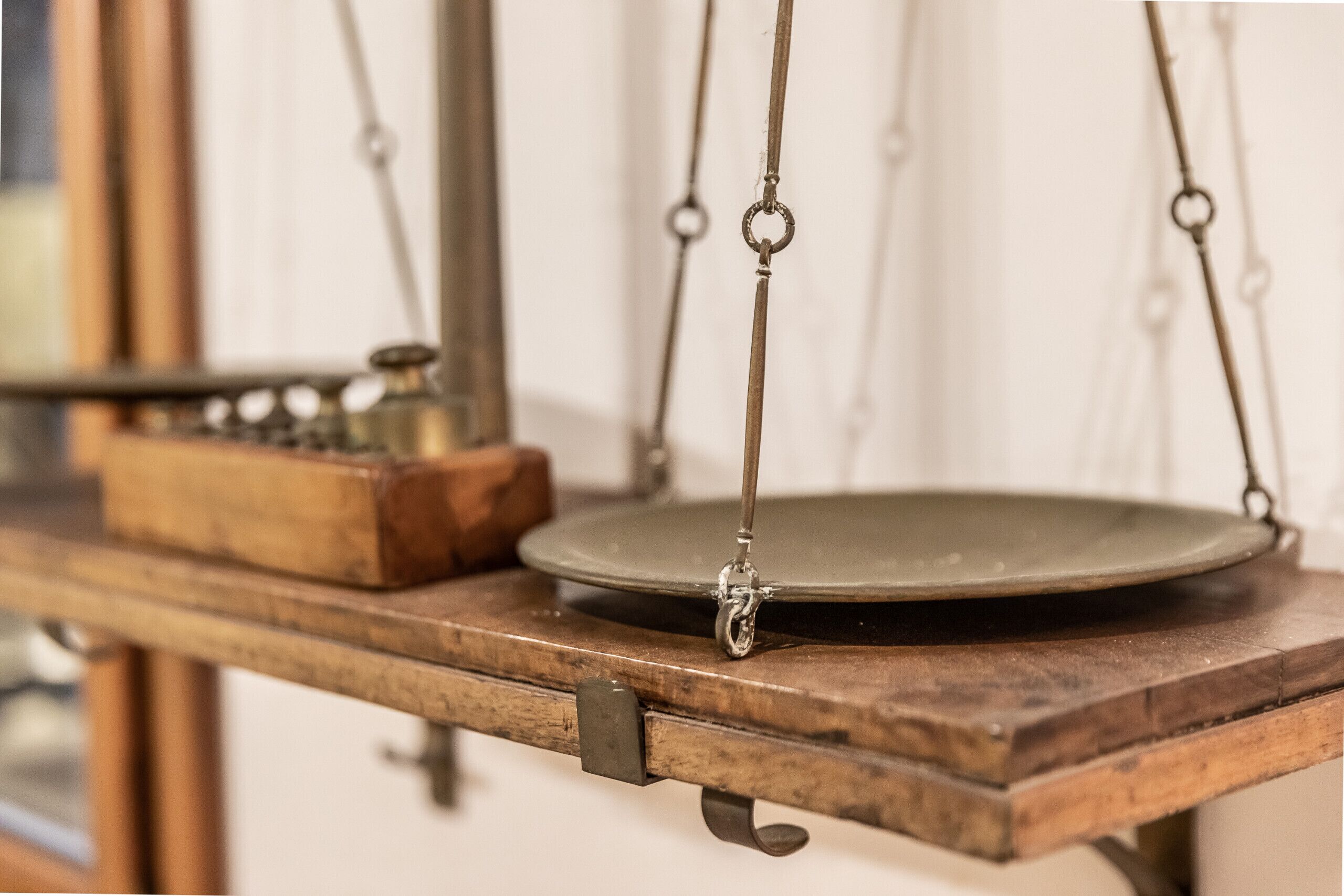 Een oude weegschaal met houten basis en metalen onderdelen.
