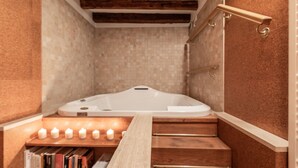 Een badkamer met een vrijstaand bad, houten treden en een plank met boeken.