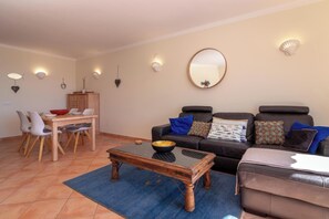 Uma sala de estar com uma mesa de jantar, cadeiras, um sofá e uma mesa de centro.