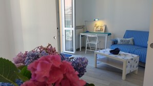 A room with a blue sofa, a white desk, and a small table with a decorative item. - BLURAPALLO wi-fi and vistamare CITRA 010046-lt-0294 CIN IT010046C2RZLGCYU4 (RAPALLO)
