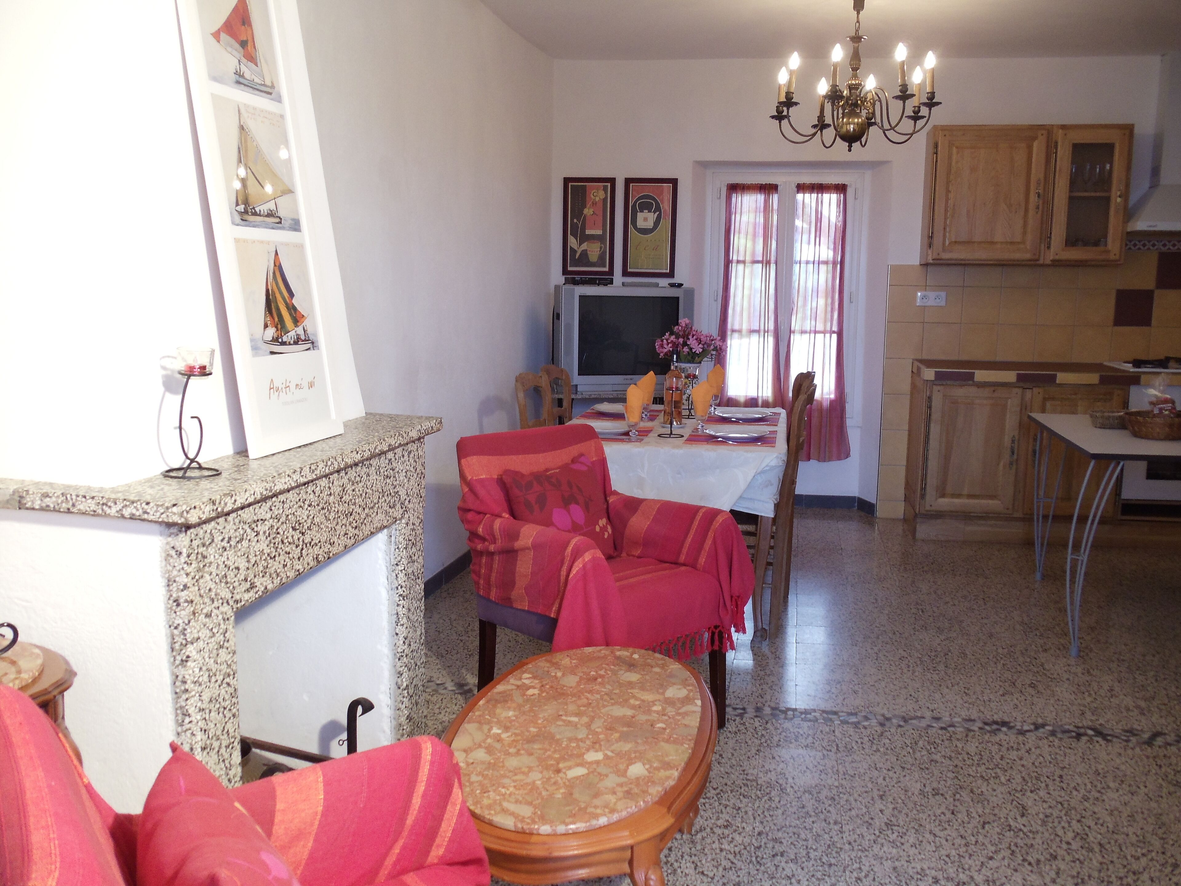 A living room with a dining area, a television, and a kitchen in the background.