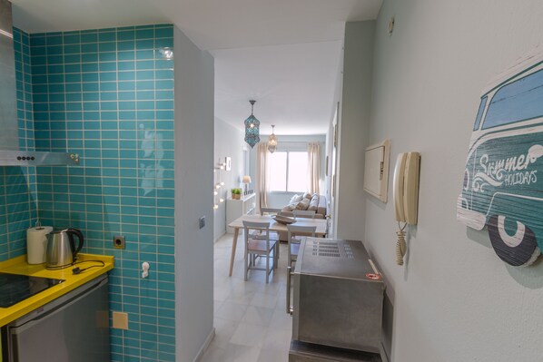 Een keuken met blauwgroene tegels, een geel aanrecht en een roestvrijstalen koelkast.