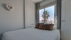 Una camera da letto con un letto grande, una finestra con tende e vista su palme.