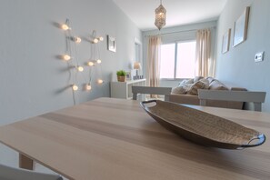 Een moderne woonkamer met een houten eettafel, een decoratieve schaal, sfeerverlichting en een bank.