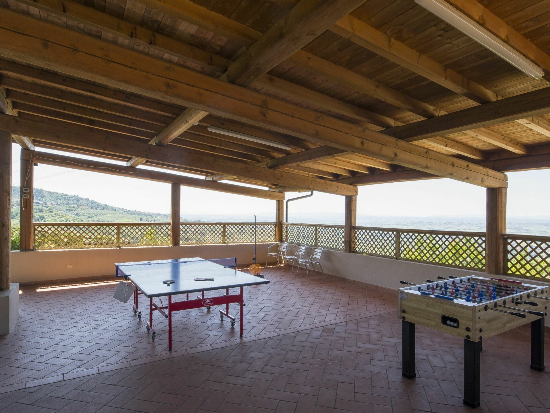 Ein Indoor-Erholungsbereich mit Tischfußball und Pingpong, Holzboden und Blick auf eine grüne Landschaft.