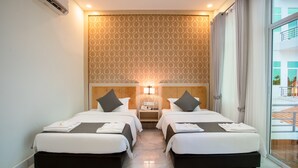 Habitación de hotel con dos camas, un papel tapiz estampado, una mesita de noche con un teléfono y vistas al exterior.