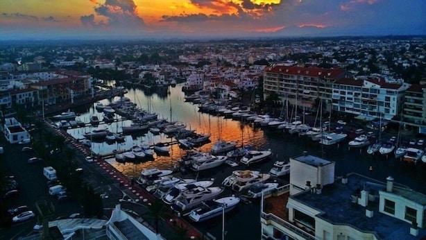 A marina with numerous boats docked, surrounded by buildings and a cityscape in the background. -  Apartment 1st Line Beach-WIFI-A / A (Empuriabrava)