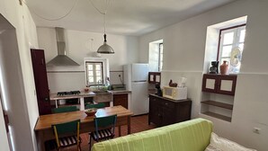 Una cocina compacta con comedor, un sofá verde y un ventanal con vistas.