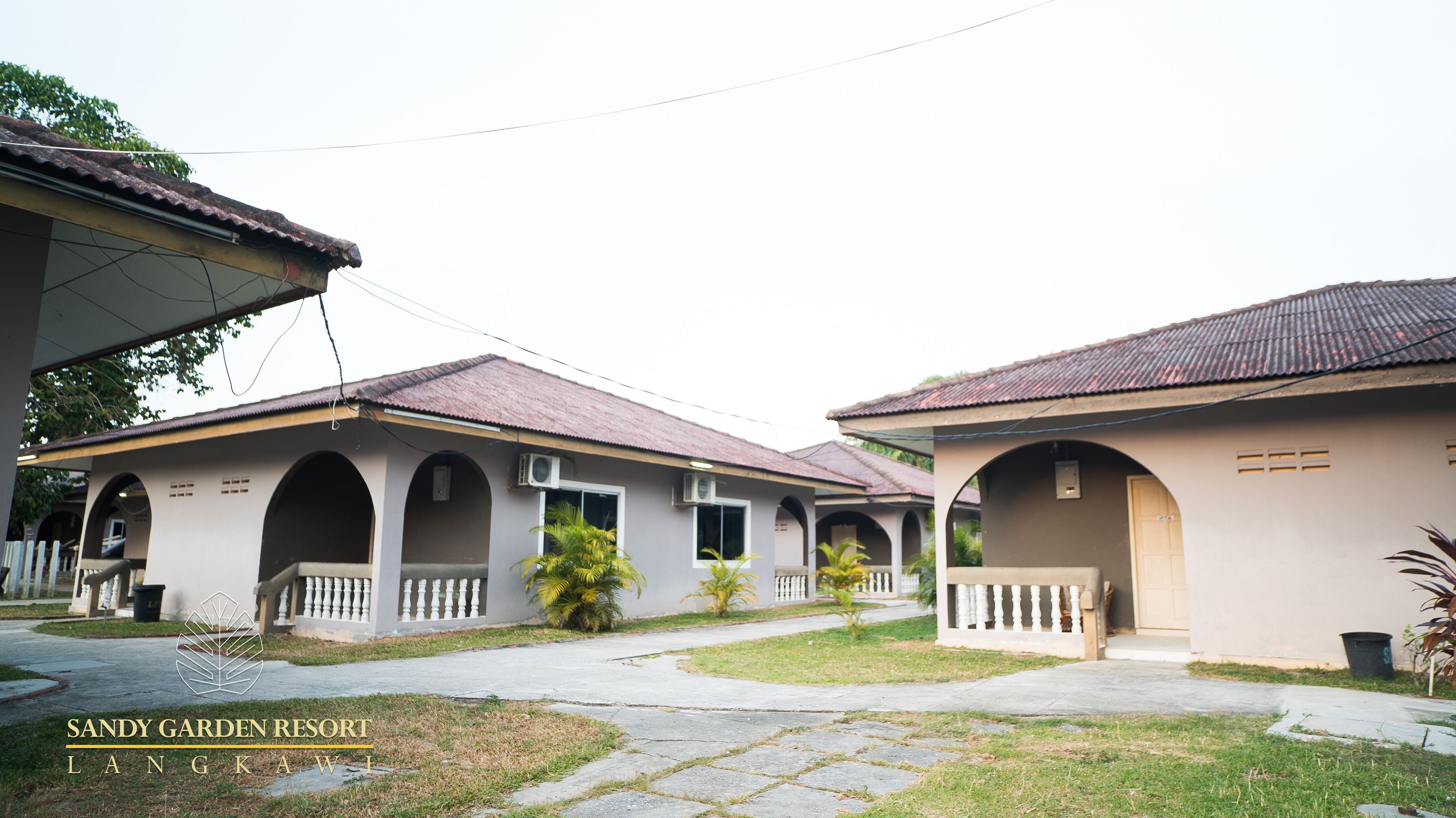 A resort with multiple buildings, each featuring arched windows and a tiled roof.