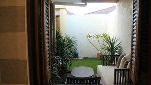 A patio area with a table and chairs, surrounded by potted plants and a small lawn. - Sandy Garden Resort (Langkawi)
