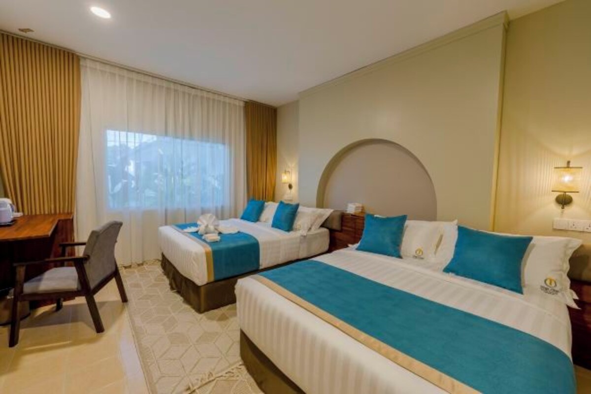Habitació d'hotel amb dos llits, una taula de treball i una cadira.