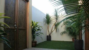 A courtyard with a wooden door, artificial grass, and potted plants. - Sandy Garden Resort (Langkawi)