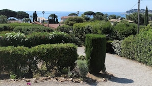 A garden with neatly trimmed hedges and a gravel path leading to a building with a tiled roof. - Nice apartment for 4 people with WIFI, TV, terrace and pets allowed (Pardigon)