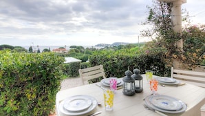 An outdoor dining table set with plates, cutlery, and glasses, overlooking a scenic landscape with greenery and distant buildings. - Nice apartment for 4 people with WIFI, TV, terrace and pets allowed (Pardigon)