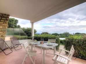 Un patio al aire libre con una mesa y sillas, un muro de piedra y vistas al paisaje.