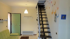 A living room with a green sofa, a white bench, a staircase, and a wall with butterfly decals. - Apartment/ flat - Marina di Massa (Marina di Massa)