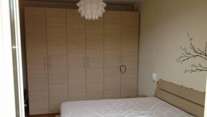 A bedroom with a bed, wooden wardrobe, and a wall-mounted light fixture. - Apartment/ flat - Marina di Massa (Marina di Massa)