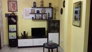 A living room with a TV, shelves with decorative items, a cabinet, and a small table with a vase. - HOUSE "SAN MIGUEL" Entire apartment "<br>Free WIFI (Morro Jable)