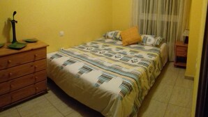 A small bedroom with a bed, a wooden dresser, a nightstand, and a window with curtains. - HOUSE "SAN MIGUEL" Entire apartment "<br>Free WIFI (Morro Jable)