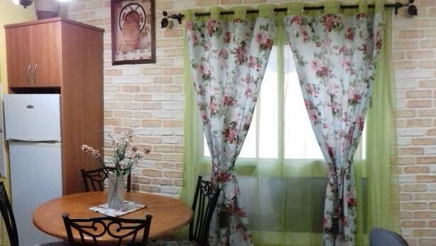 A dining area with a round table, chairs, a vase with flowers, a wooden cabinet, and a wall-mounted air conditioner. - HOUSE "SAN MIGUEL" Entire apartment "<br>Free WIFI (Morro Jable)