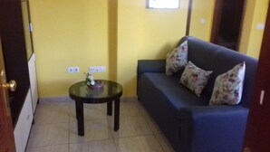 A room with a blue sofa, a glass table with a flower vase, and a tiled floor. - HOUSE "SAN MIGUEL" Entire apartment "<br>Free WIFI (Morro Jable)