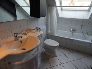 Een bad/douchecombinatie, handdoeken, zeep, toiletpapier