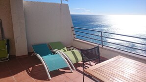 A balcony with a view of the sea, a wooden table, and two chairs with cushions. - PENTHOUSE PANORAMIC VIEWS (Montroig)