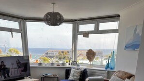 Un salon moderne avec une grande fenêtre, un téléviseur, une table basse et un canapé.