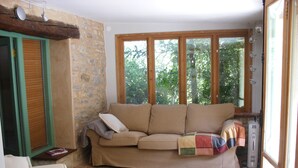 Un salon chaleureux avec un canapé, un tapis à motifs et une grande fenêtre donnant sur la forêt.
