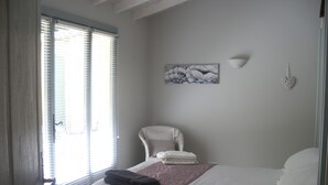 Une chambre à coucher avec un lit, une chaise, un tableau et un objet décoratif en forme de cœur accroché au mur.