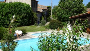 Un quartier résidentiel doté d’une piscine, de bâtiments en pierre et d’une végétation luxuriante.