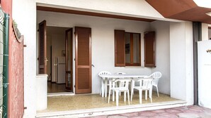 Un patio con mesa y sillas, una puerta y una ventana con contraventanas.